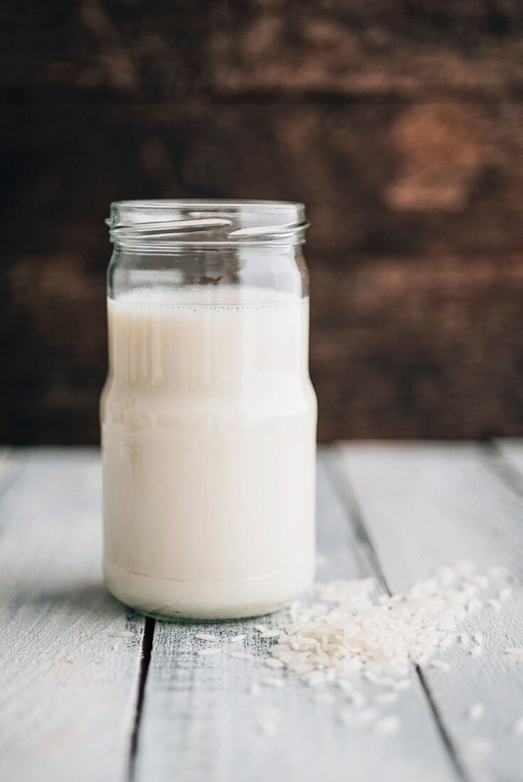 A jar of rice milk next to grains of rice