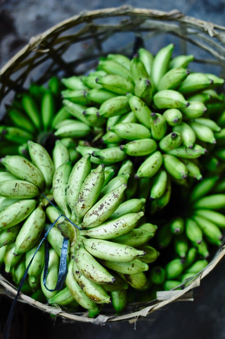 Grüne Bananen im Korb auf einem Markt in Bali