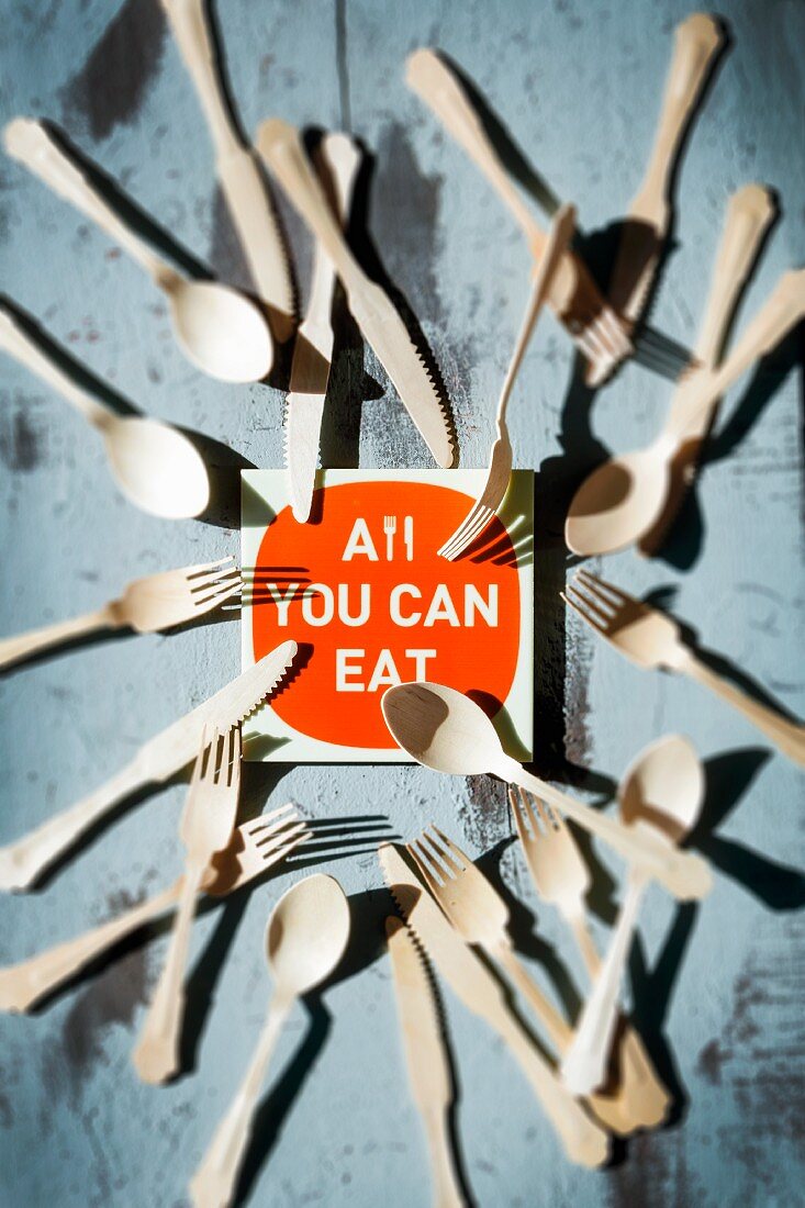 Schild mit Aufschrift: All you can eat, umgeben von Besteck