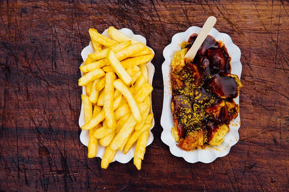 Currywurst und Pommes Frites auf Papptellern