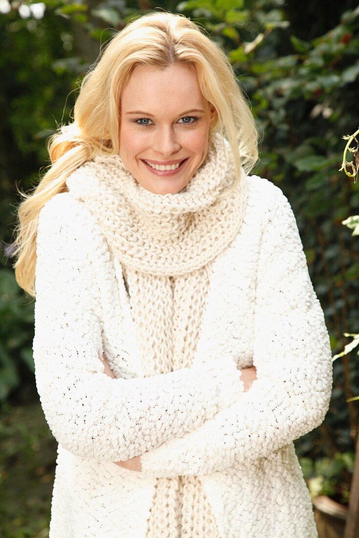 A young woman wearing a coarse-knit cardigan and scarf