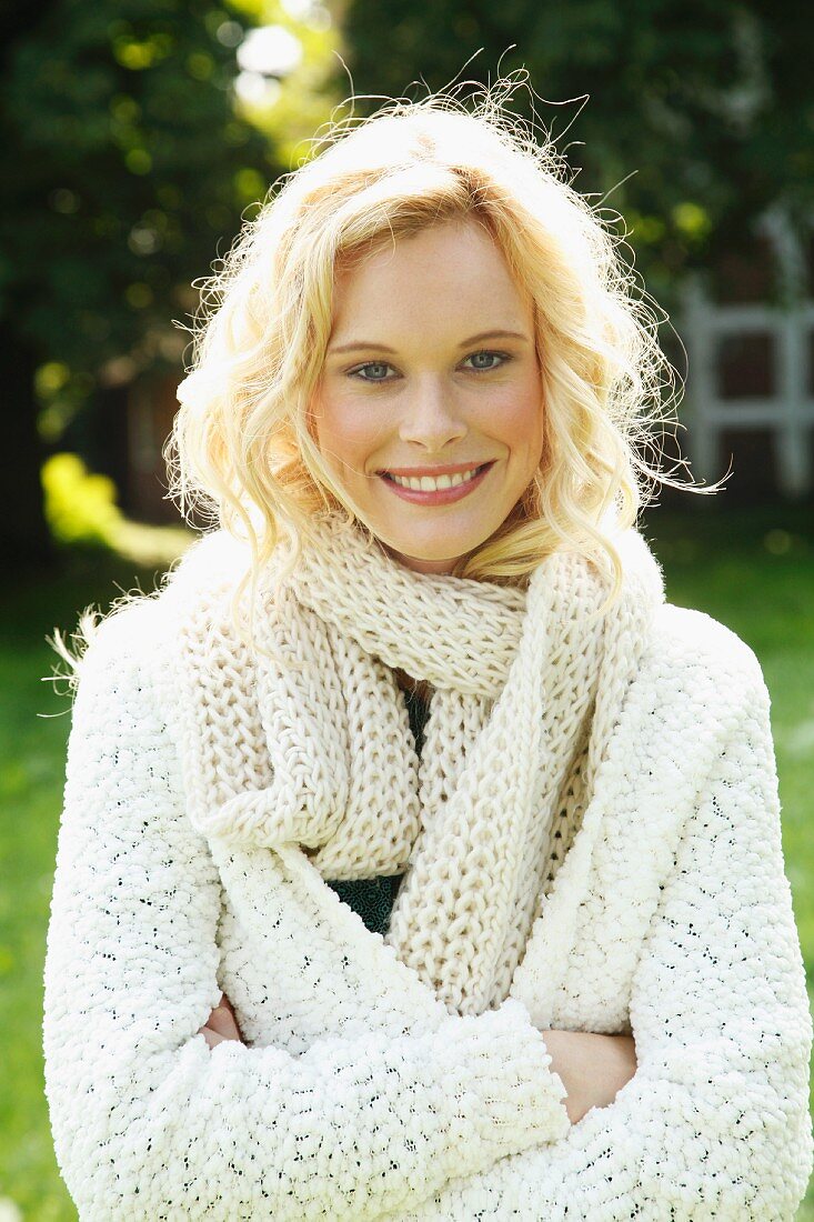 A young woman wearing a coarse-knit cardigan and scarf