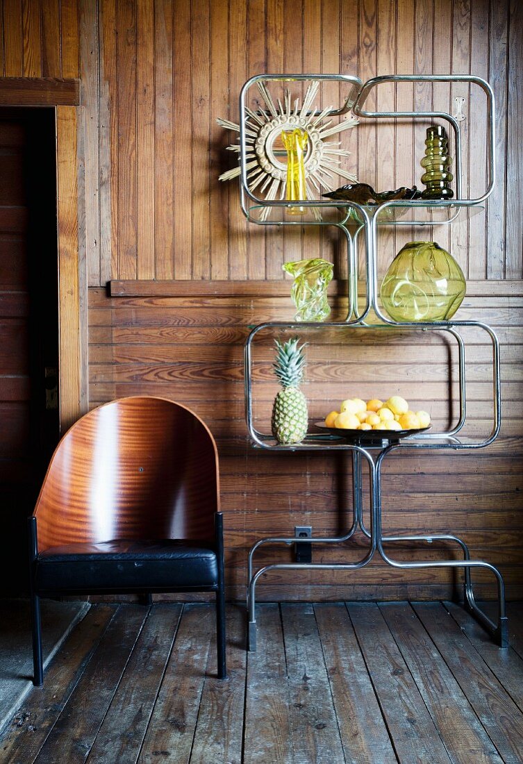 Curved metal shelving and designer chair in front of board wall