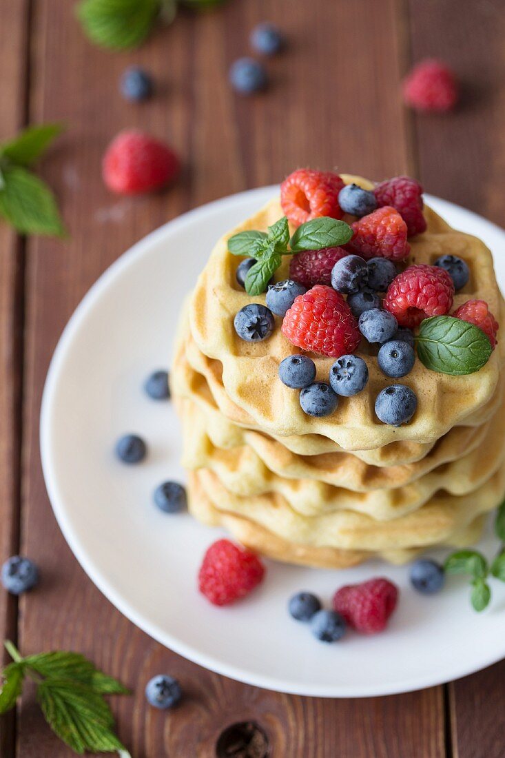 A stack of waffles with raspberries and blueberries