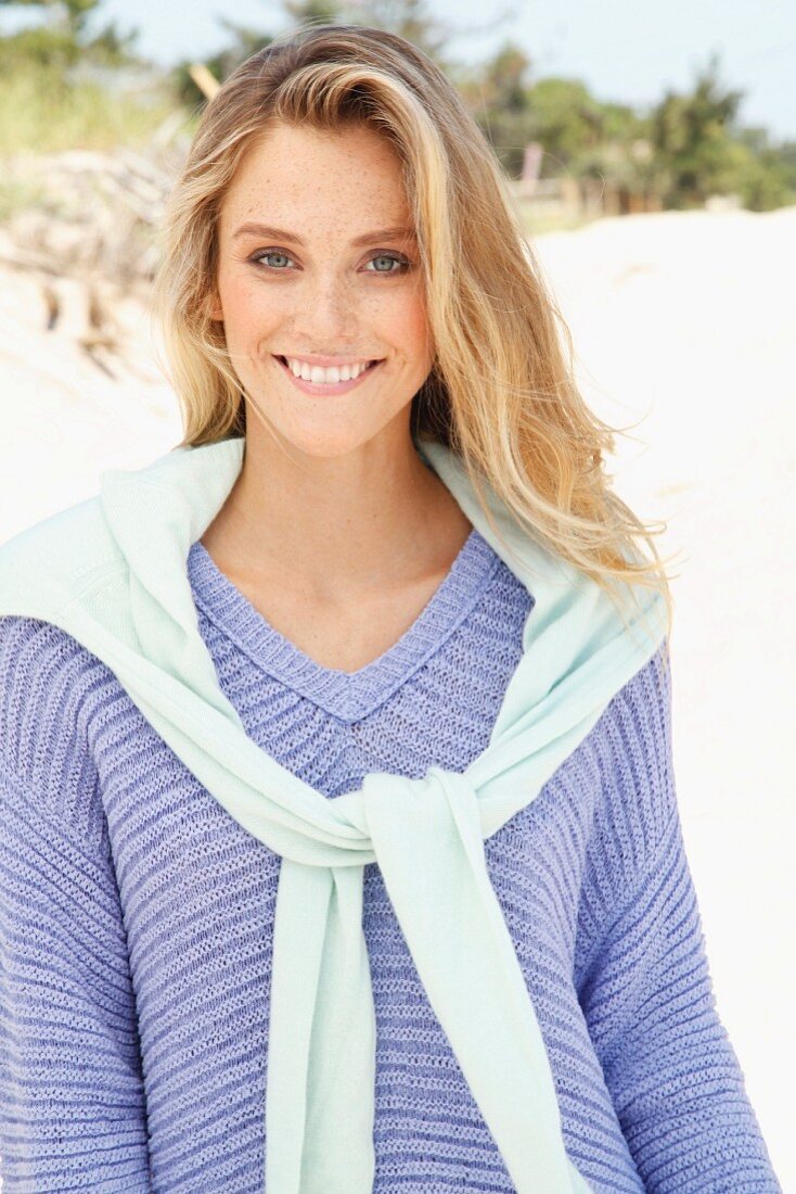 A young woman on a beach wearing a purple jumper