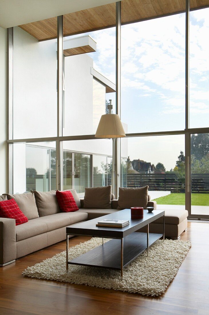 Elegant seating area with exotic-wood parquet floor, glass wall and view into garden