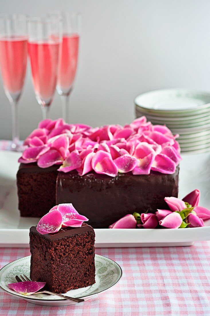 Schokoladenkuchen mit rosa Rosenblüten, serviert mit Sektcocktails