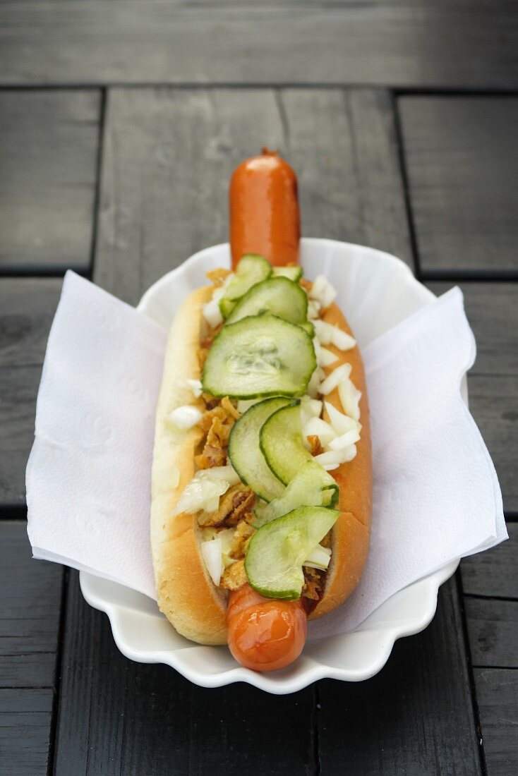 A hot dog with gherkins and roasted onions