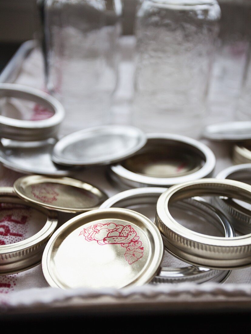 Jam jars and lids on a tray with a tea towel