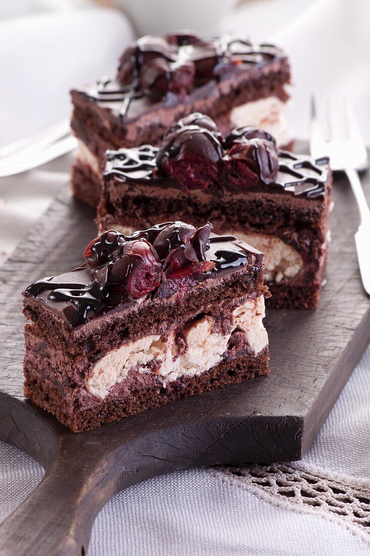 Slices of chocolate cakes with cherries and meringue