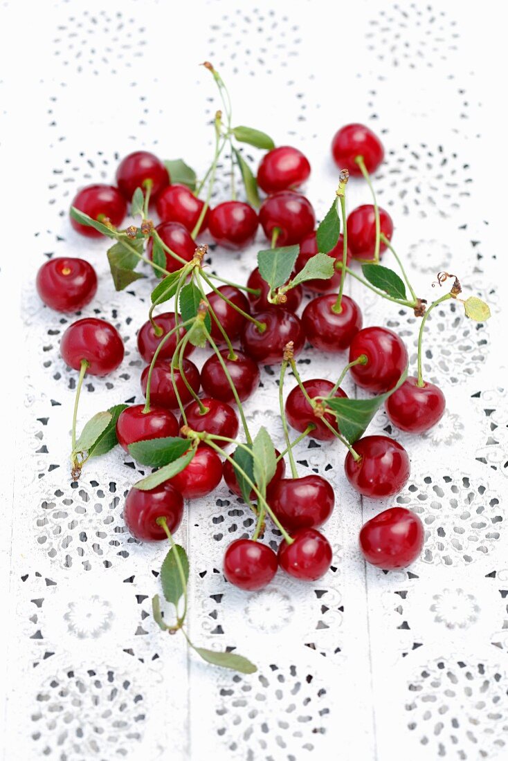 Sour cherries with leaves on a lace surface