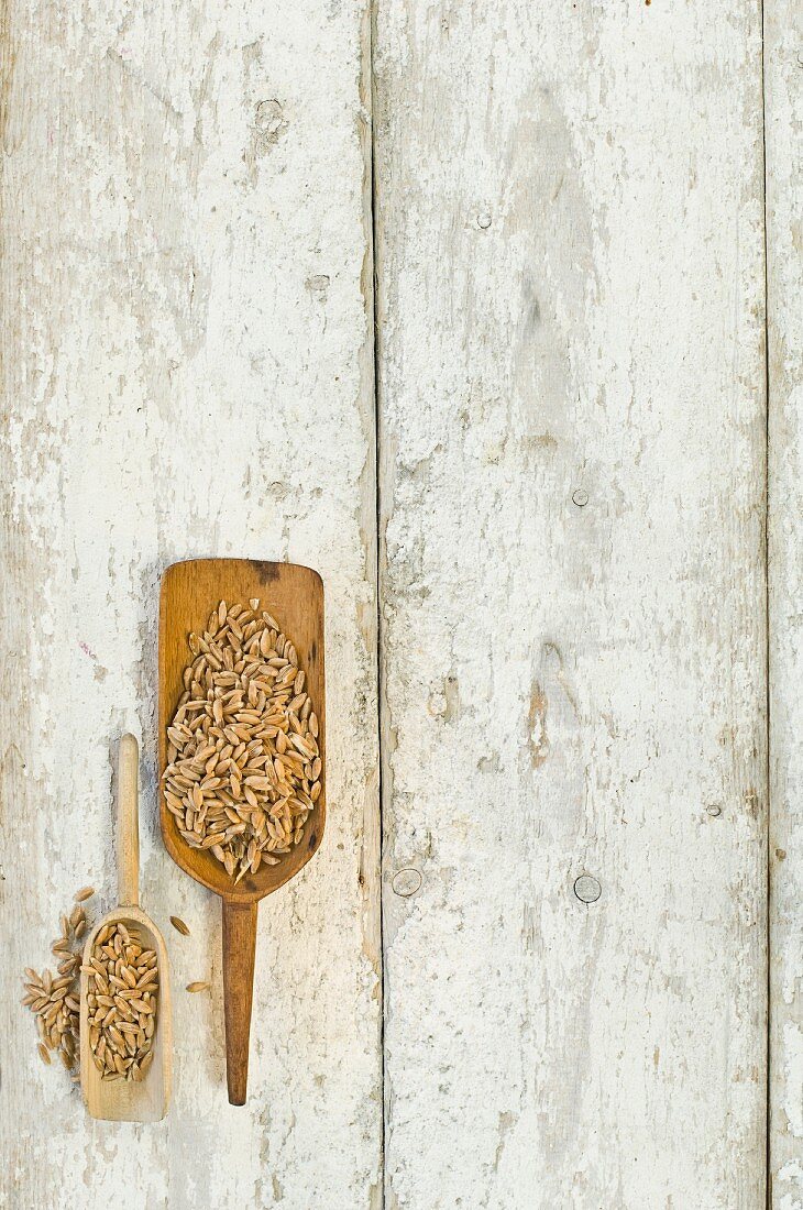 Zwei Holzschaufeln mit Dinkel auf Holzuntergrund