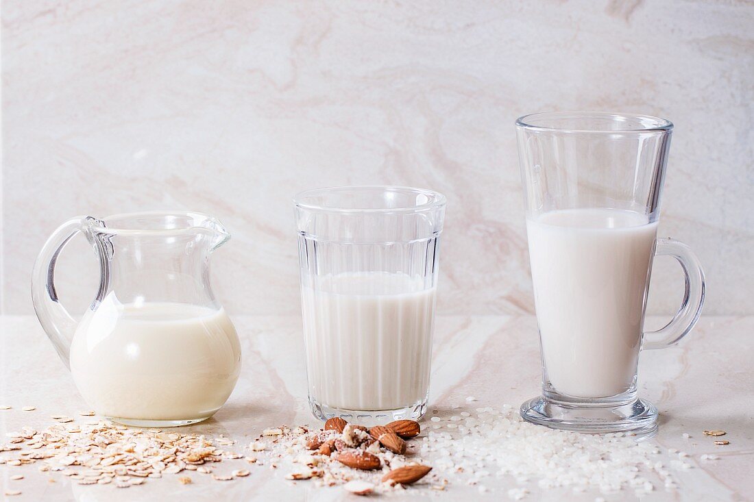 Oat milk, almond milk and rice milk on a marble surface