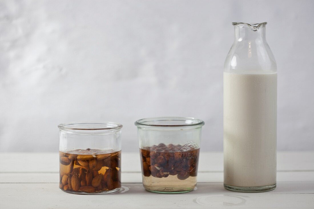 Almonds being softened in water, a jar of almonds and a bottle of nut milk