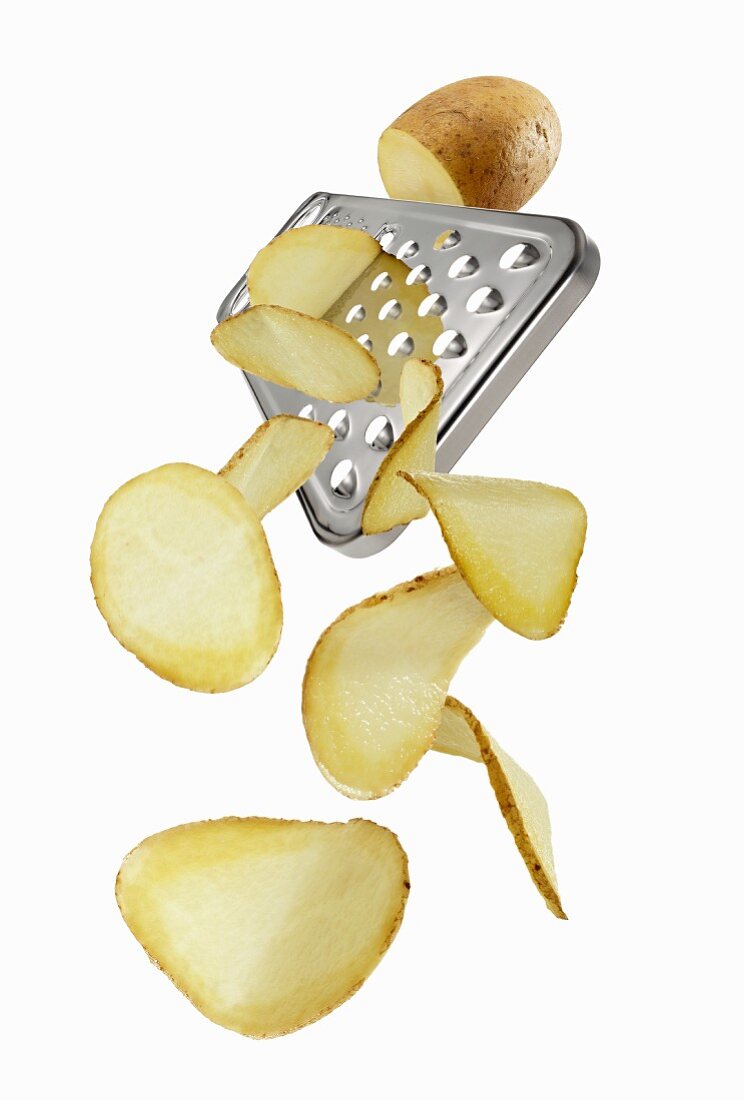 A vegetable grate with a potato and potato slices
