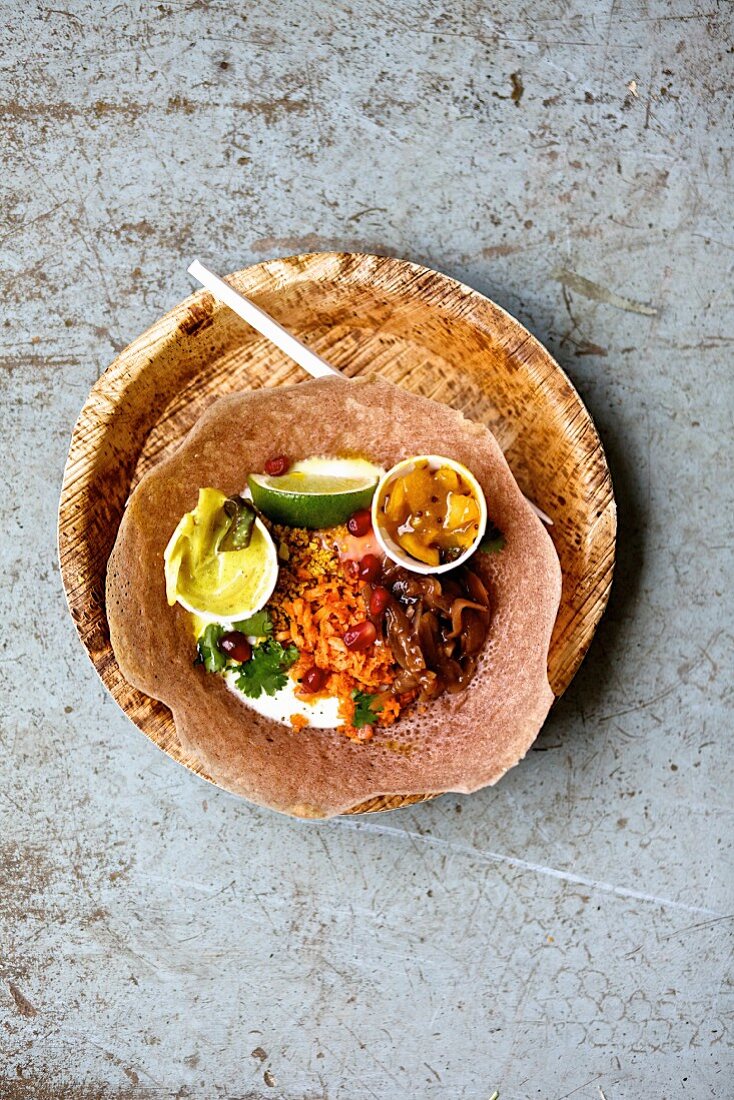 Egg hopper: a rice flour and coconut milk crepe with pickles, carrots, onions, peanuts, coriander, pomegranate seeds, curry and lemon chutney (Indonesia)