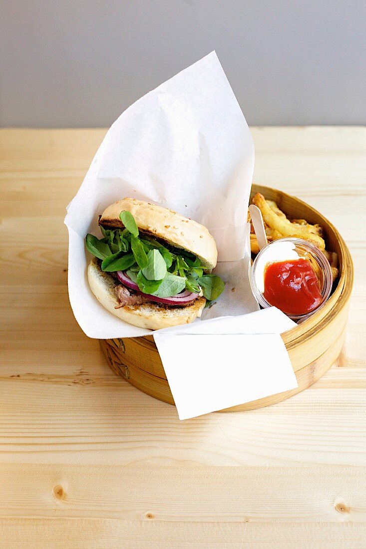 A tuna fish burger with shiso, red onions, chips, ketchup and mayonnaise