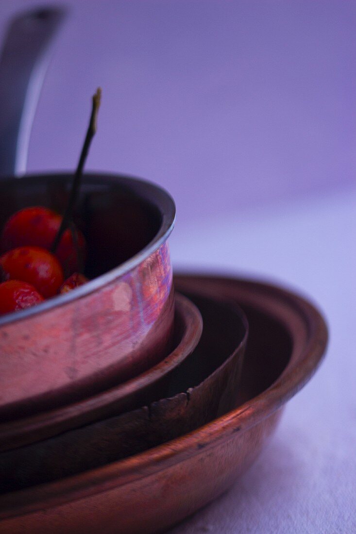 A stack of copper pans with cherry tomatoes