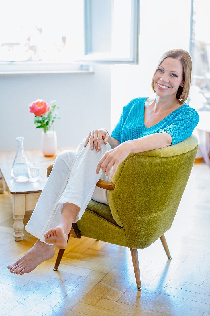 A woman sitting sideways in a green upholstered armchair