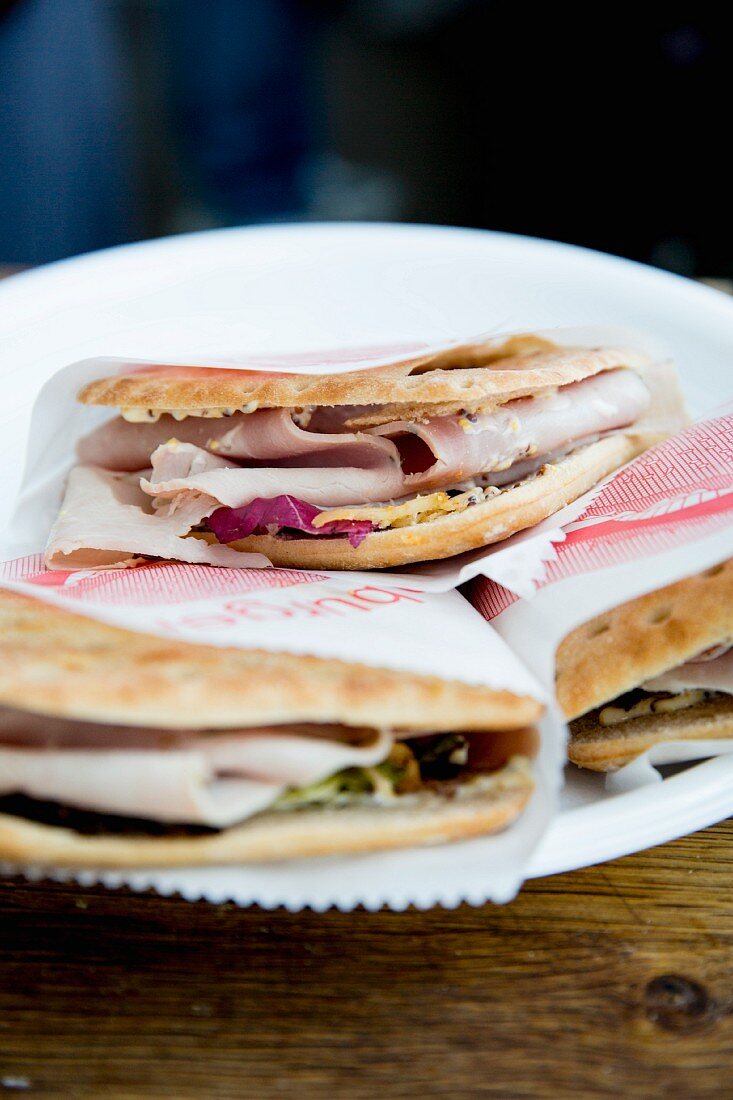 Fladenbrot-Sandwiches mit Schinken in Papier gewickelt auf Teller