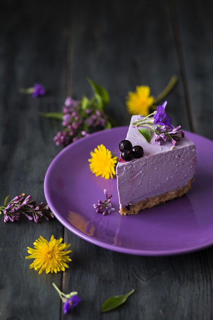 A slice of blueberry cheesecake with dandelions and violets