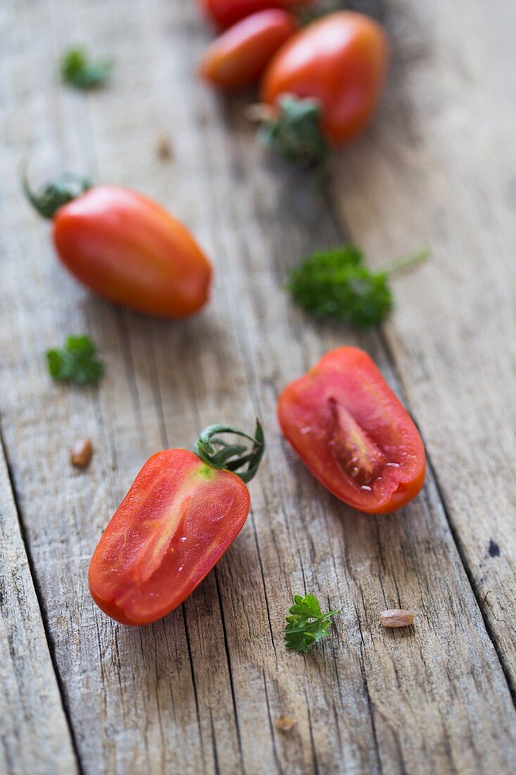 Cherry tomatoes, whole and halved, on a wooden surface