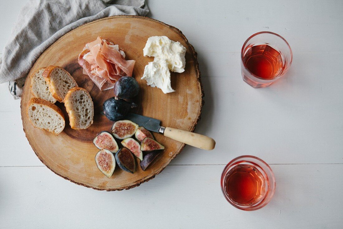 Parma ham, figs, bread and cream cheese on a wooden platter