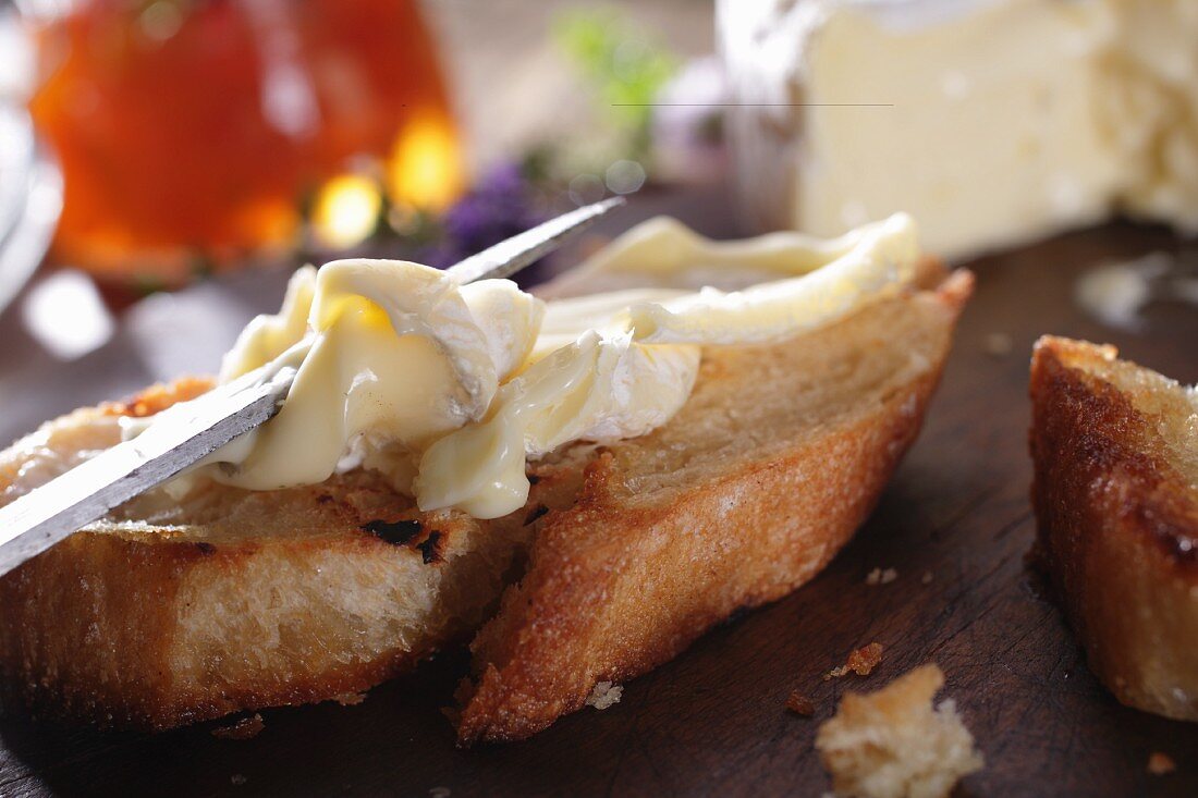 Baguettescheibe mit Camembert bestreichen