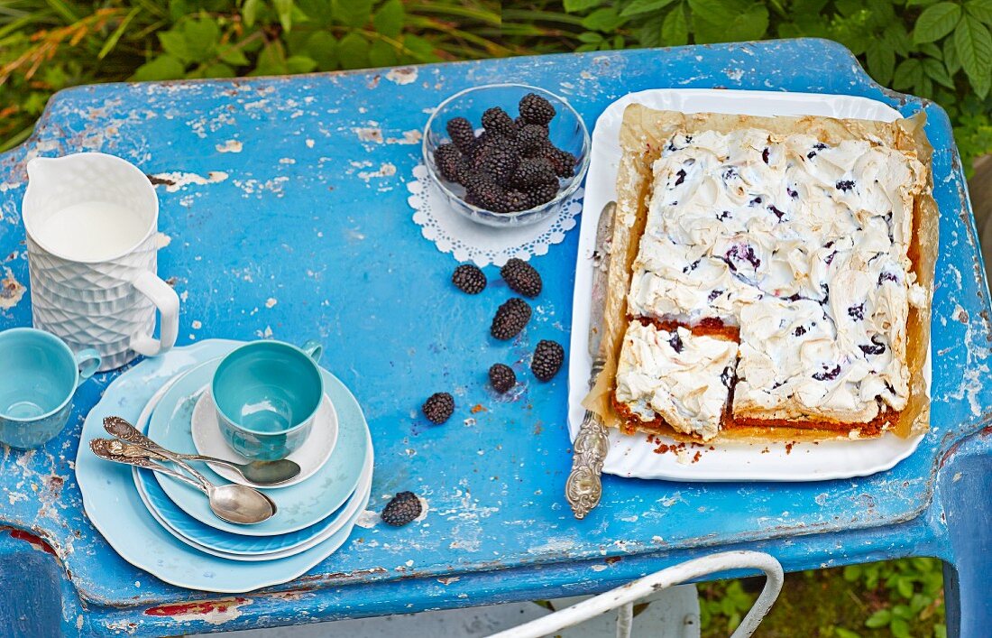 blackberry and meringue slices and coffee crockery on a garden table