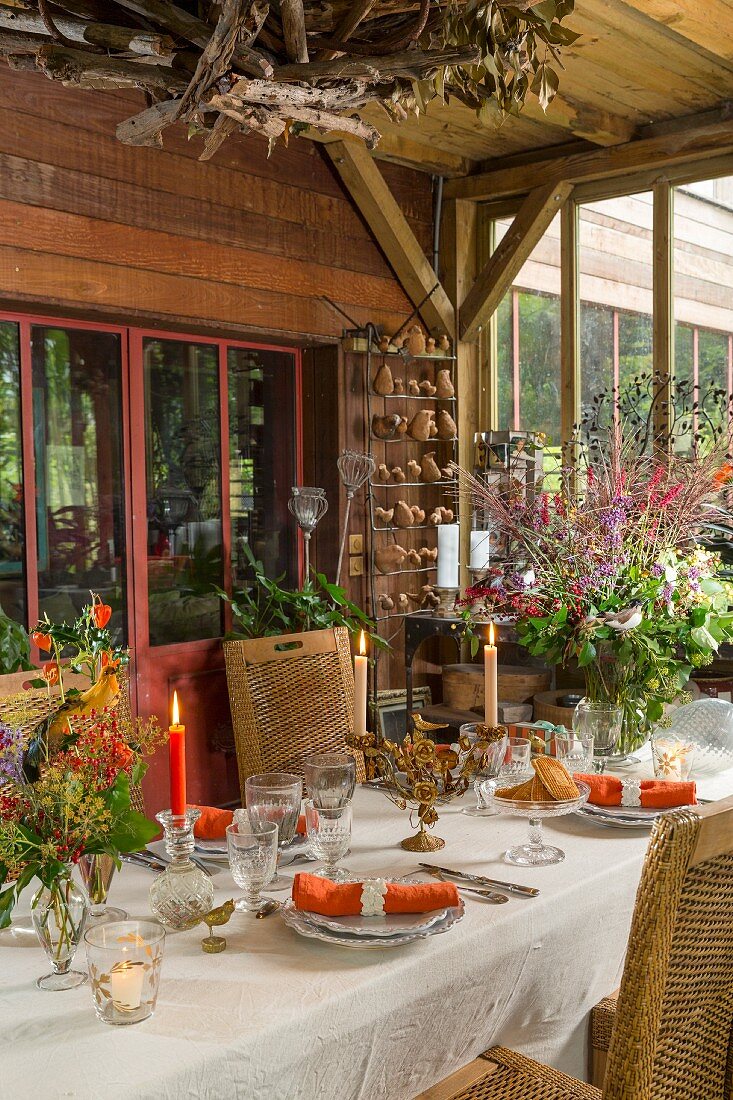 Herbstlich gedeckte Tafel im Wintergarten mit Bretterwand