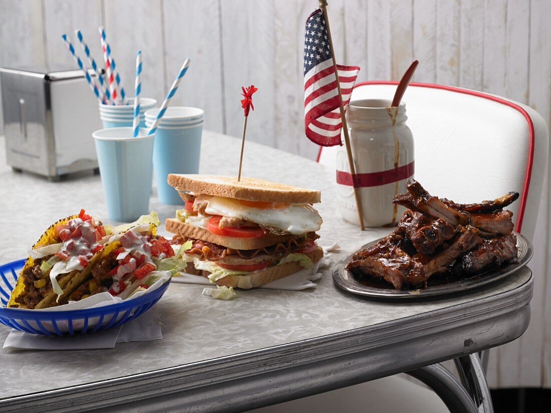 Taco shells, a club sandwich and spare ribs on a table (USA)