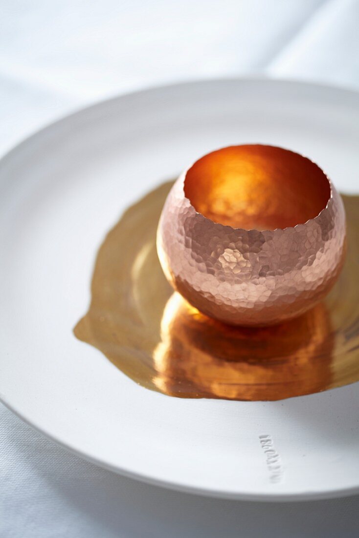 A copper dish on a white plate with gold decoration