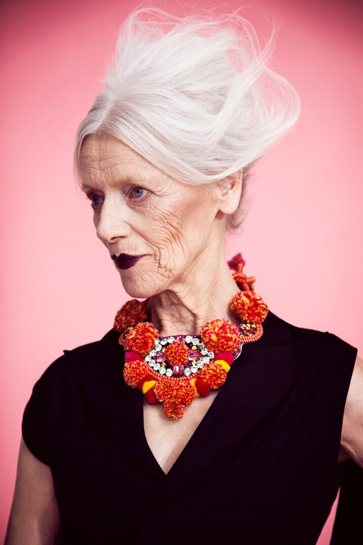 A grey-haired woman wearing a pom-pom necklace