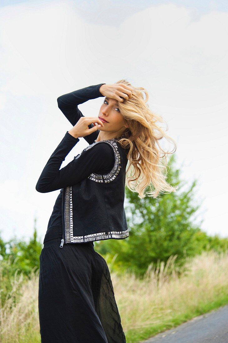 A woman dressed in black on the side of a road