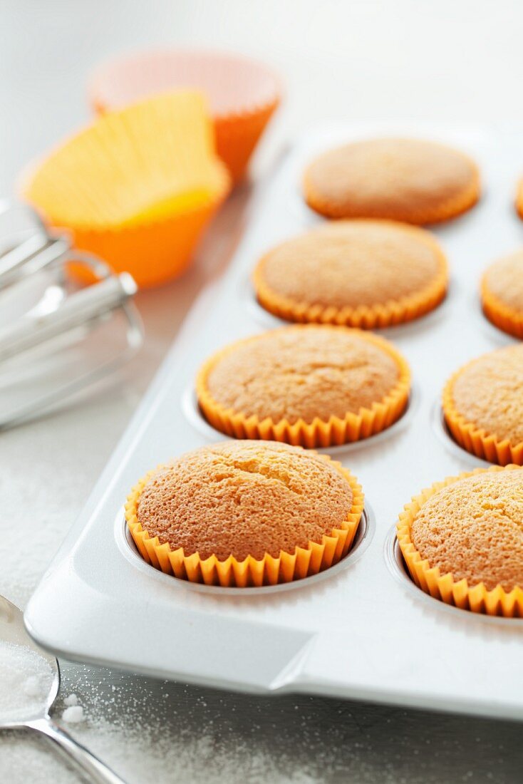 Freshly baked cupcakes in orange paper cases
