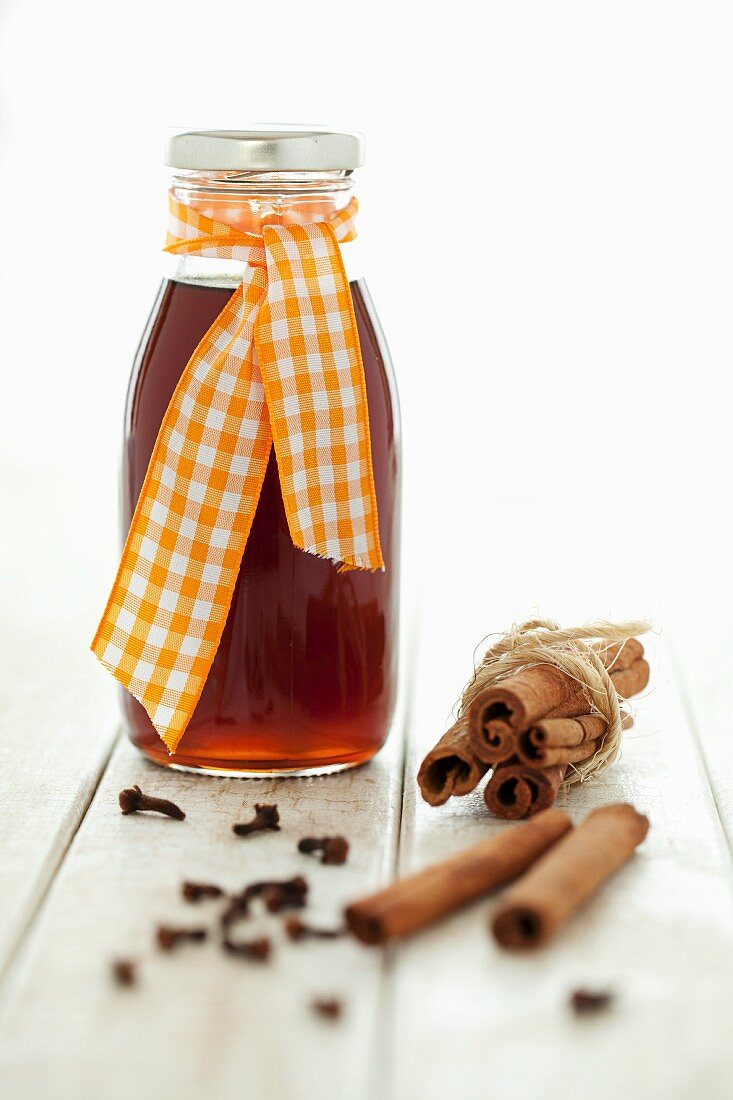 A bottled of spiced syrup with cinnamon and cloves
