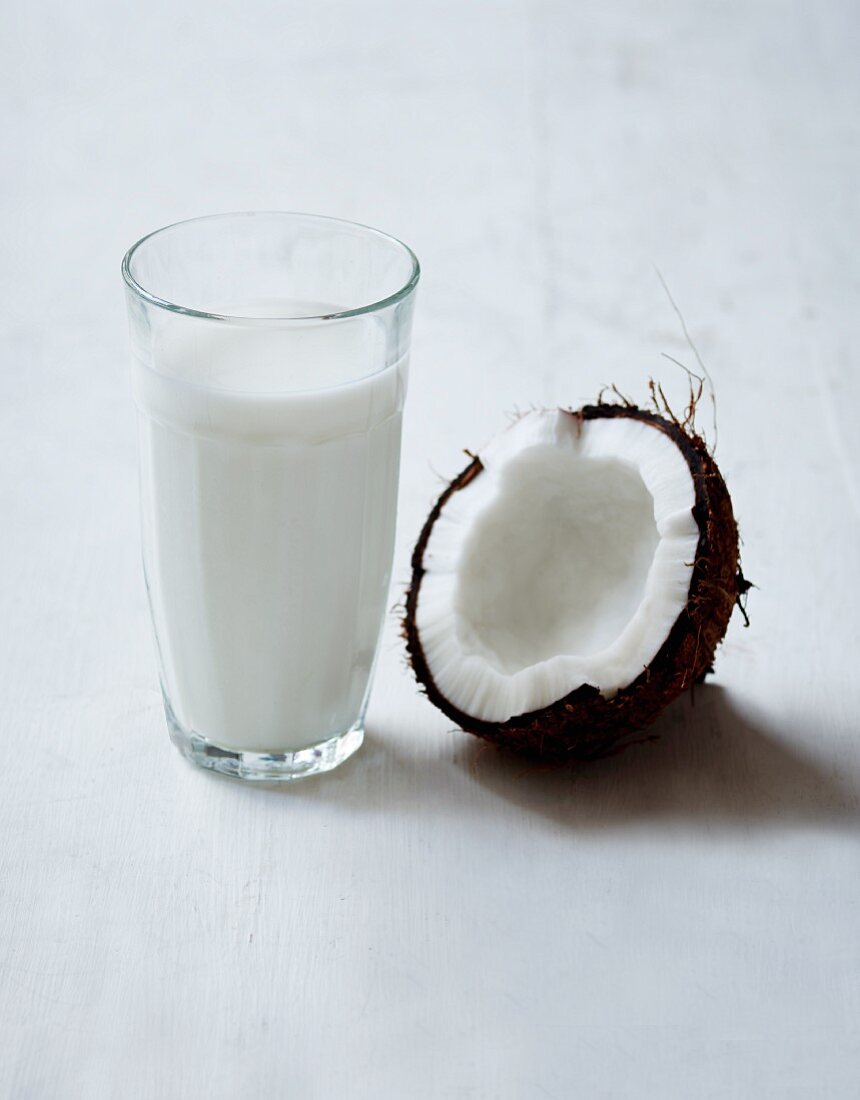 Halbe Kokosnuss und ein Glas Kokosmilch