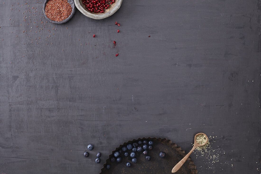 Blueberries and pomegranate seeds on a black surface