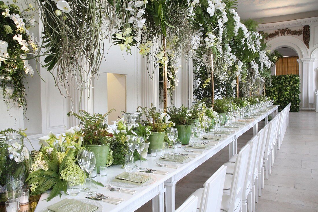 Festliche Hochzeitstafel mit grün-weisser Blumendeko in einem Saal