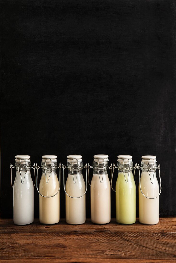 Various types of milk substitutes in bottles with their ingredients: coconut milk, soya milk, rice milk, almond milk, Edamame milk, oat milk