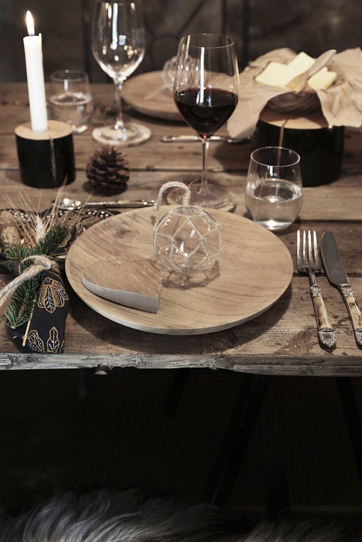 Christmas in a wine cellar: a place setting at a rustic wooden table with wine and candles