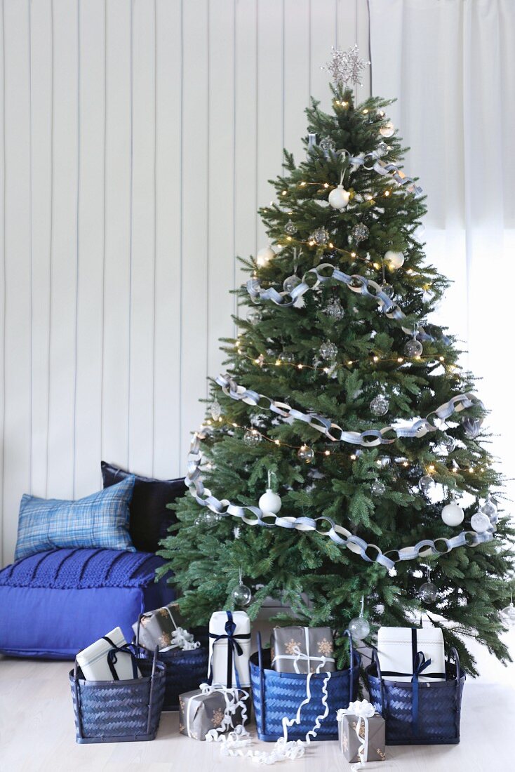 Gifts in blue baskets below decorated Christmas tree