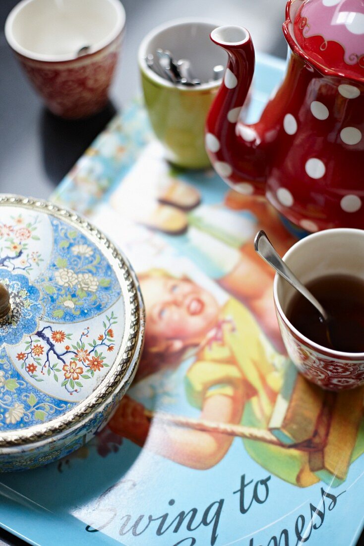 Kaffeegeschirr und bemalte Zuckerdose aus Porzellan auf Tablett mit Retro Bild