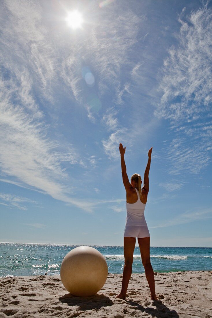 A woman on a beach doing yoga stretching