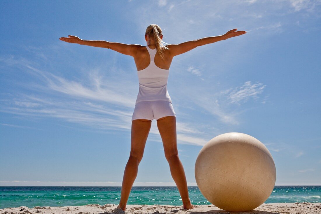 A woman practising yoga on a beach