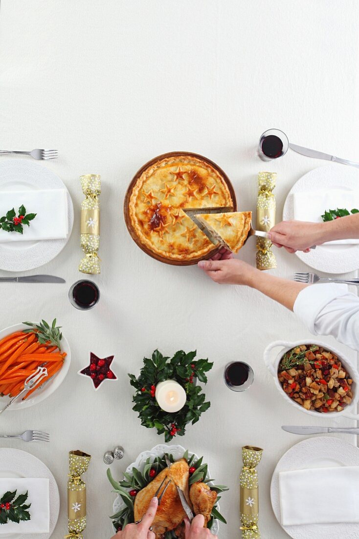 A table laid for Christmas dinner with a roast, sides and a sliced pie