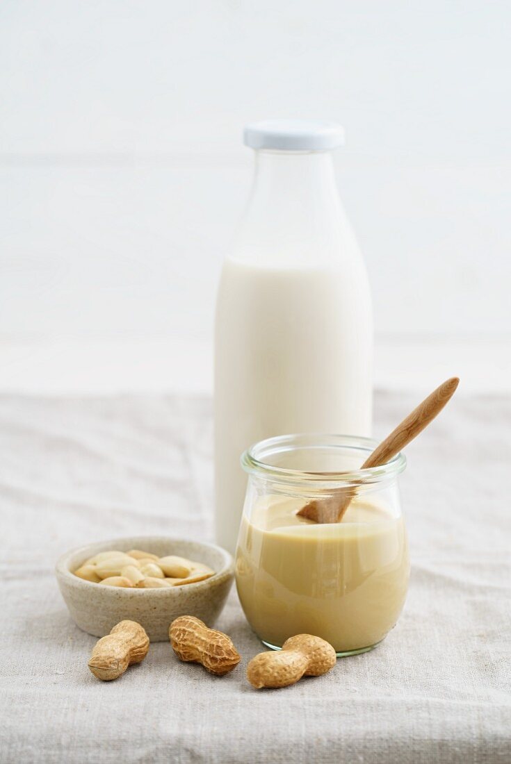 Erdnussmus im Glas und Erdnussmilch in einer Glasflasche