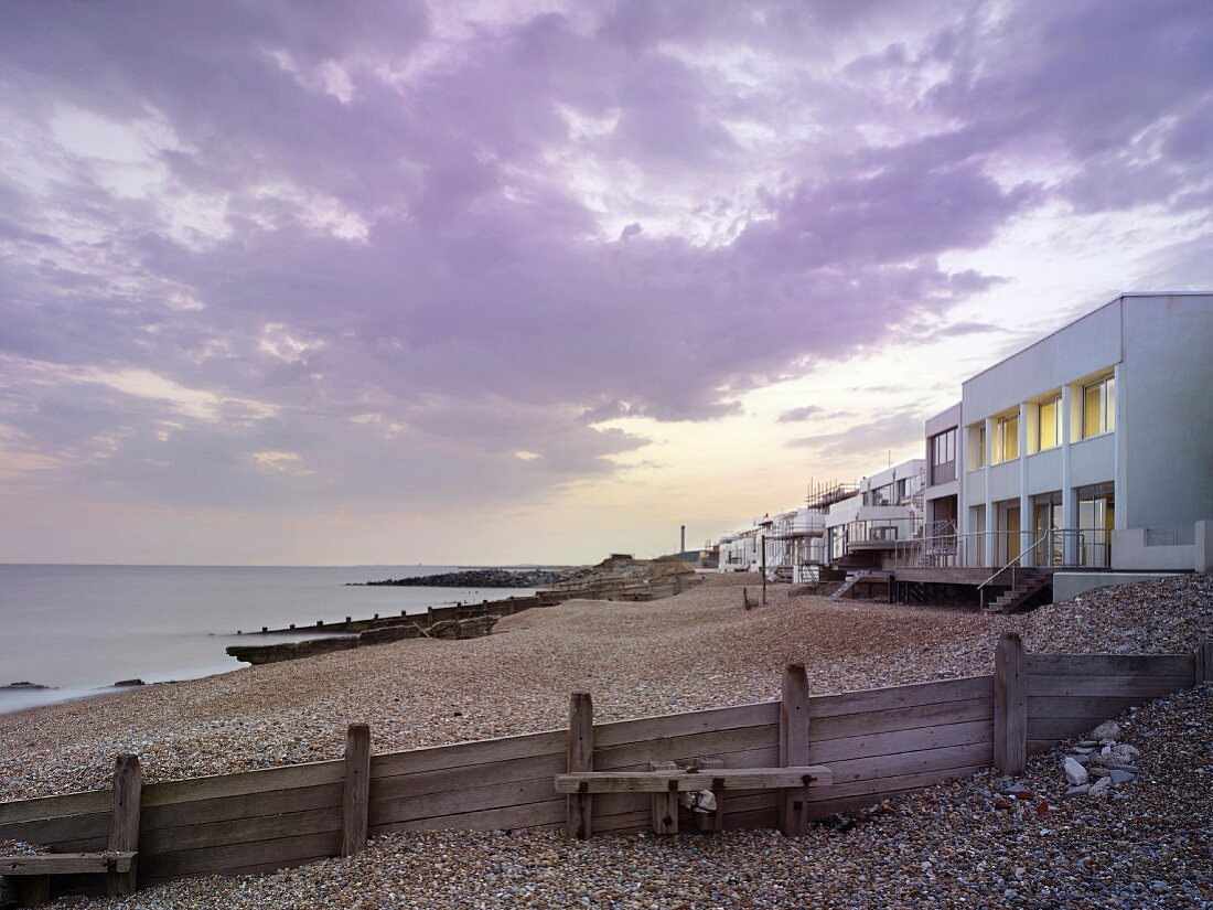 Meeresküste mit Wolkenstimmung, Kiesstrand und modernen Strandhäusern