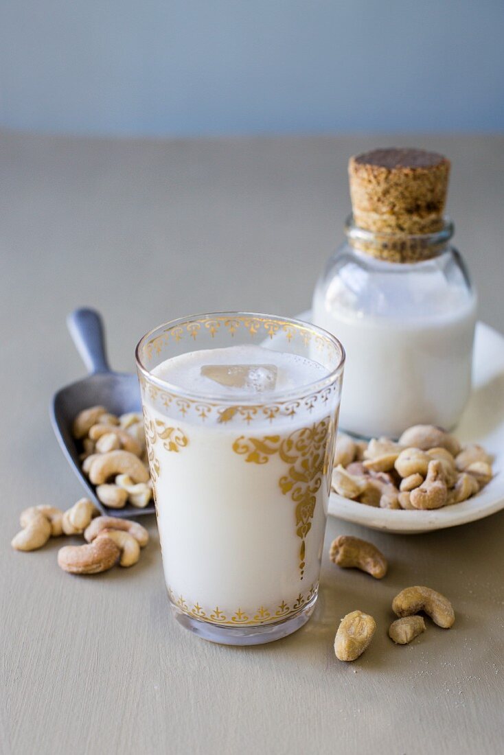 Cashew milk in gold-embossed glass with scattered cashew nuts