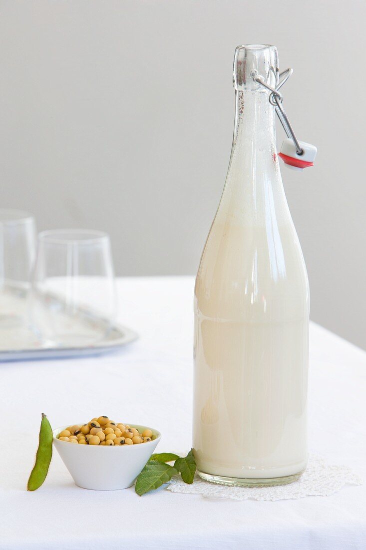 A bottle of soya milk and a dish of soya beans